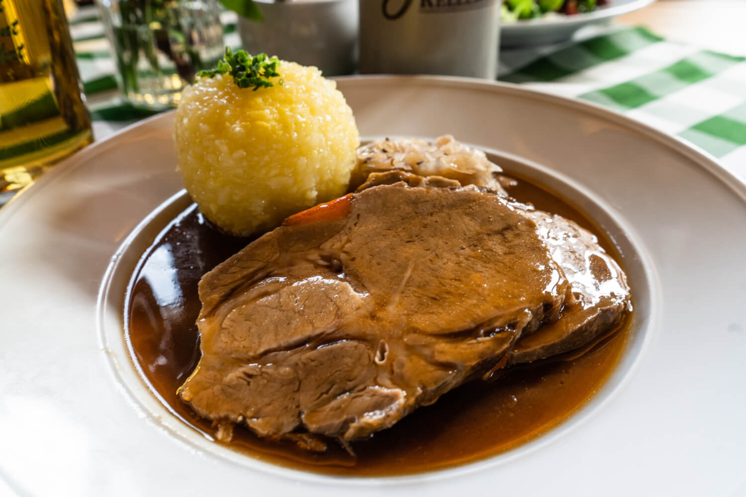 A slice of roast pork with a potato Knödel, German boiled dumpling, in a pool of gravy.