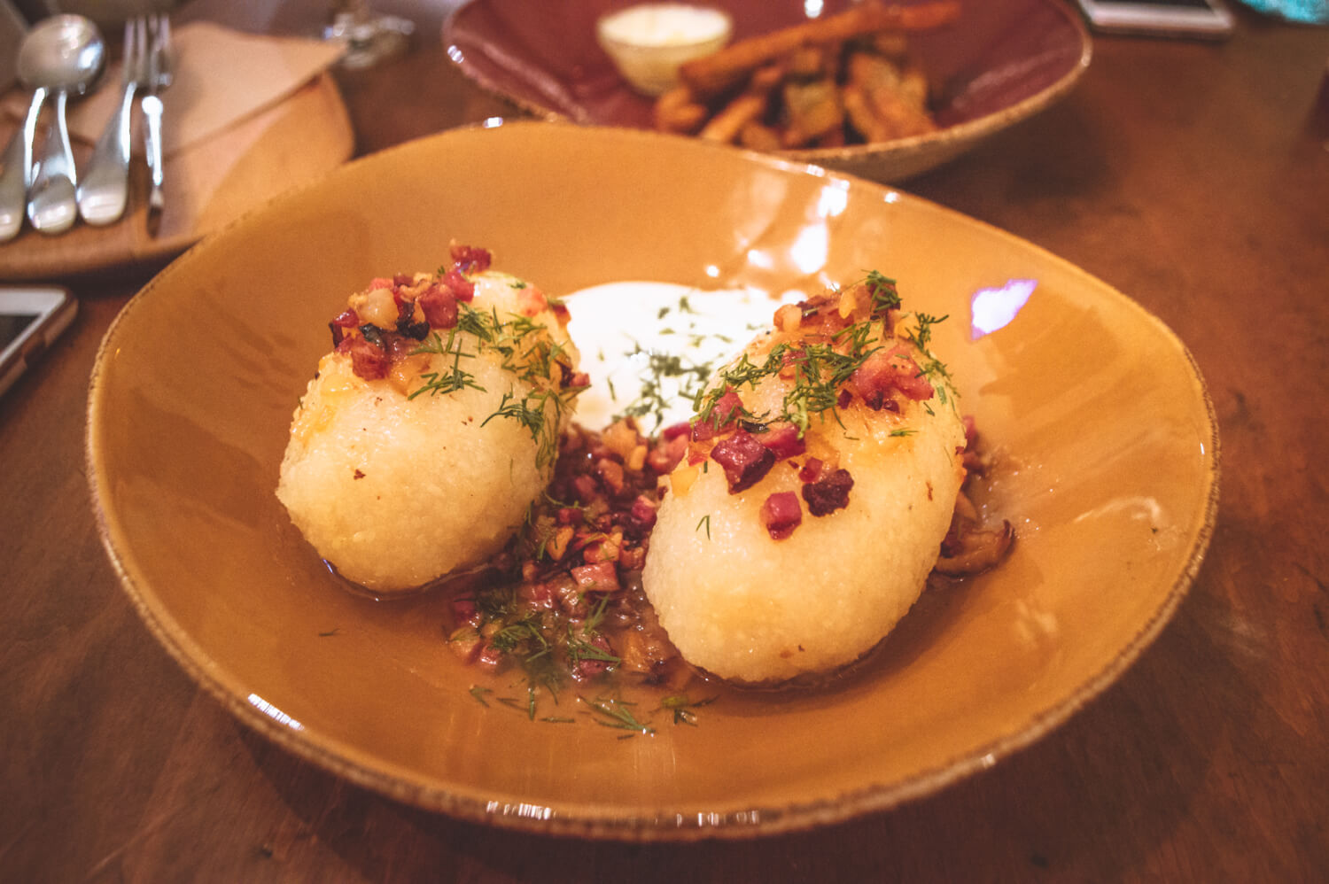 Cepelinai, Lithuanian potato dumplings filled with ground meat and topped with bacon, dill and sour cream.